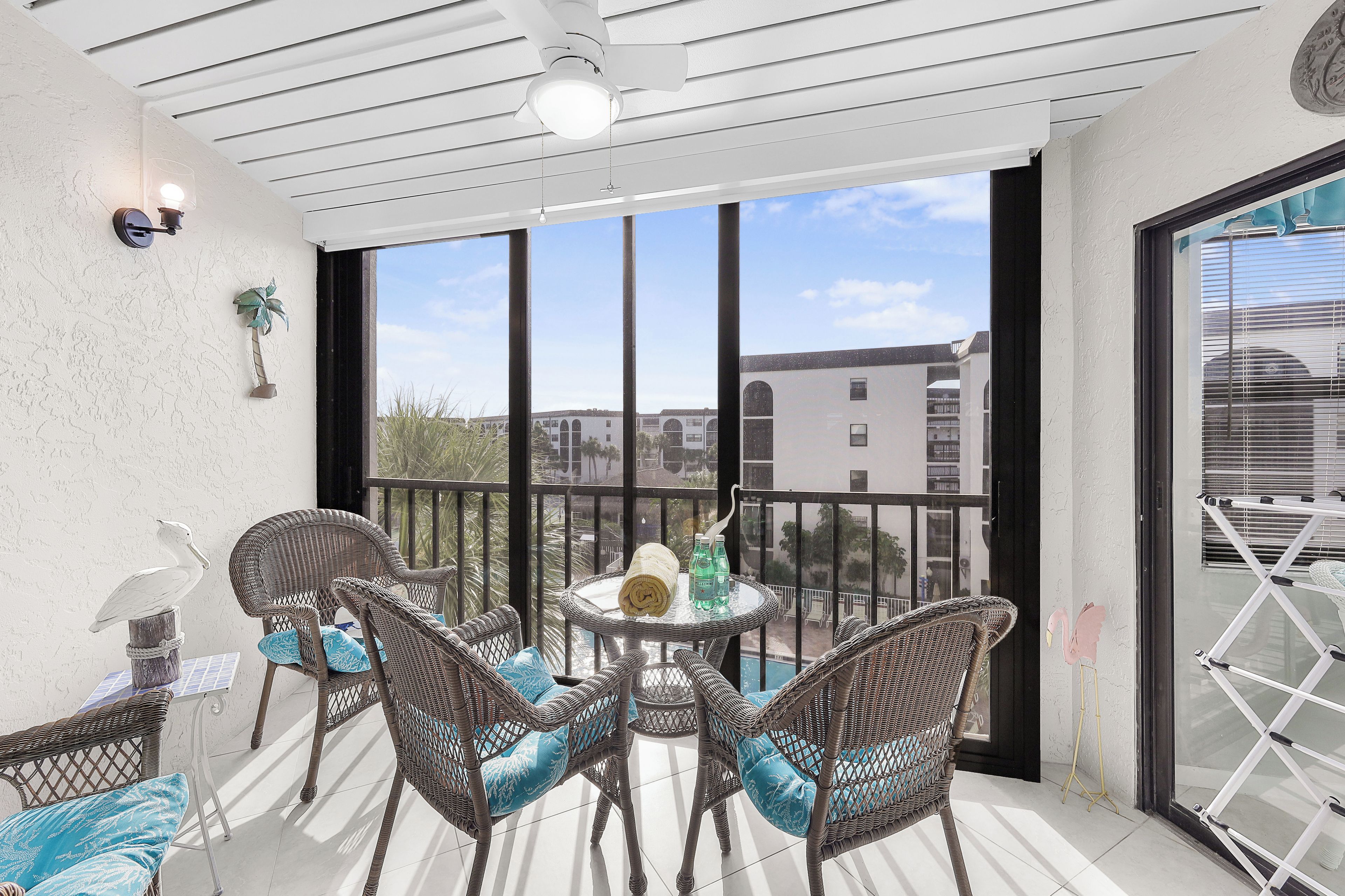 A balcony with wicker chairs, a table with a bottle and a towel, and a view of buildings in the background.