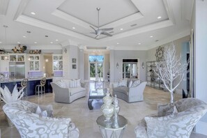 A spacious living area with a high ceiling, modern furniture, and a decorative tree.