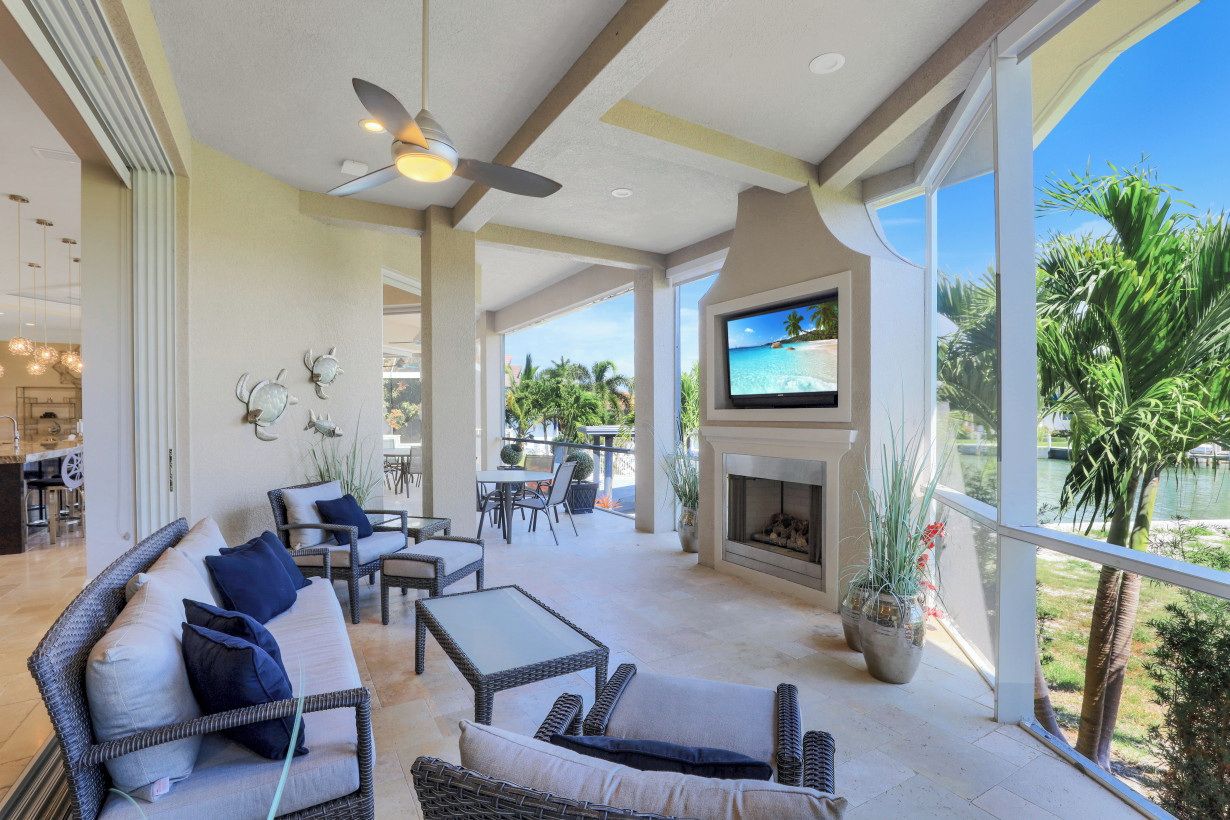 A spacious outdoor patio with wicker furniture, a flat-screen TV, and a fireplace.