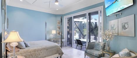 Ein Schlafzimmer mit Bett, Stuhl, Fernseher und Blick ins Freie.