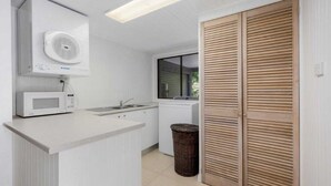 A compact kitchen with a microwave, sink, and washing machine. - Lakeside Lodge - Fabulous Waterfront Holiday (Laurieton)