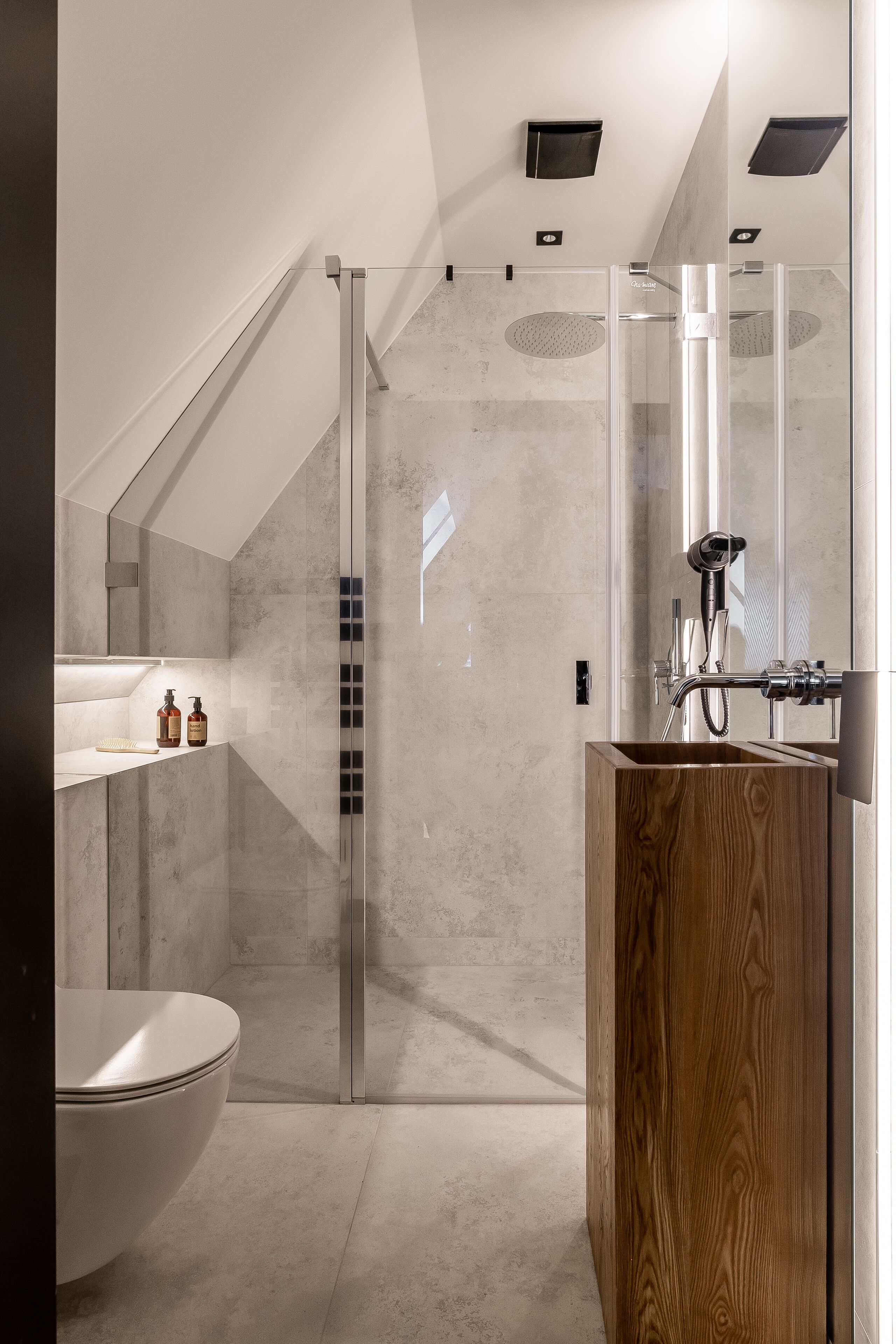 Ein modernes Badezimmer mit einer Duschkabine, einem Holzwaschtisch und einer weißen Toilette.