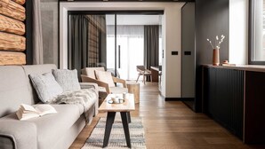 A modern living room with a sofa, chairs, a coffee table, and a view to a dining area. - Villa T Apartments & SPA (Zakopane)