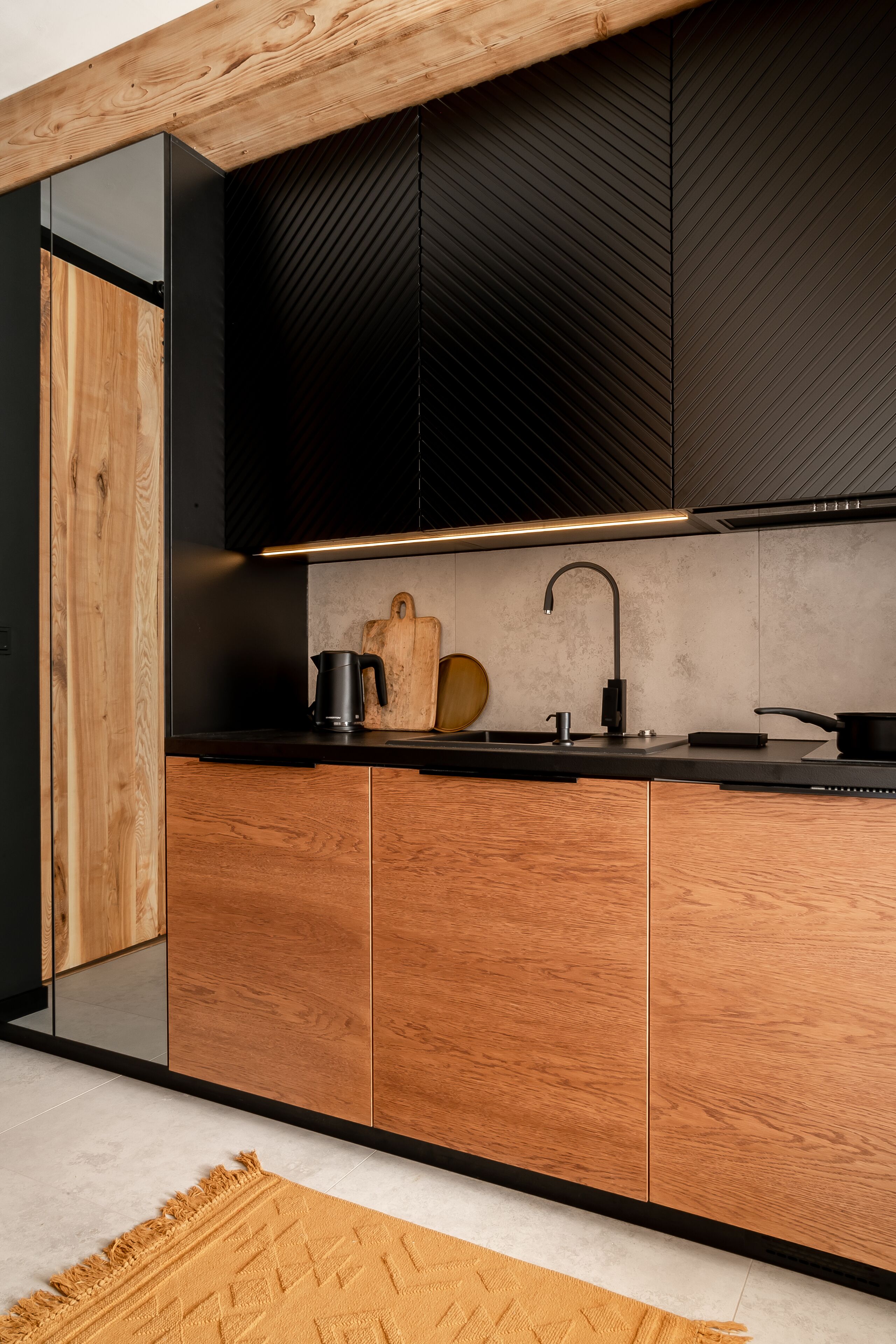 Una cocina moderna con armarios de madera, encimera negra y cocina integrada.