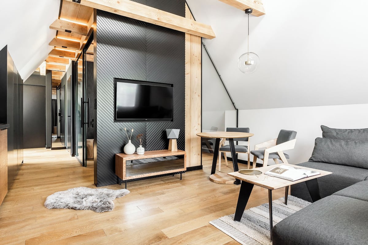 A modern living room with a flat-screen TV, wooden furniture, and a cozy rug.