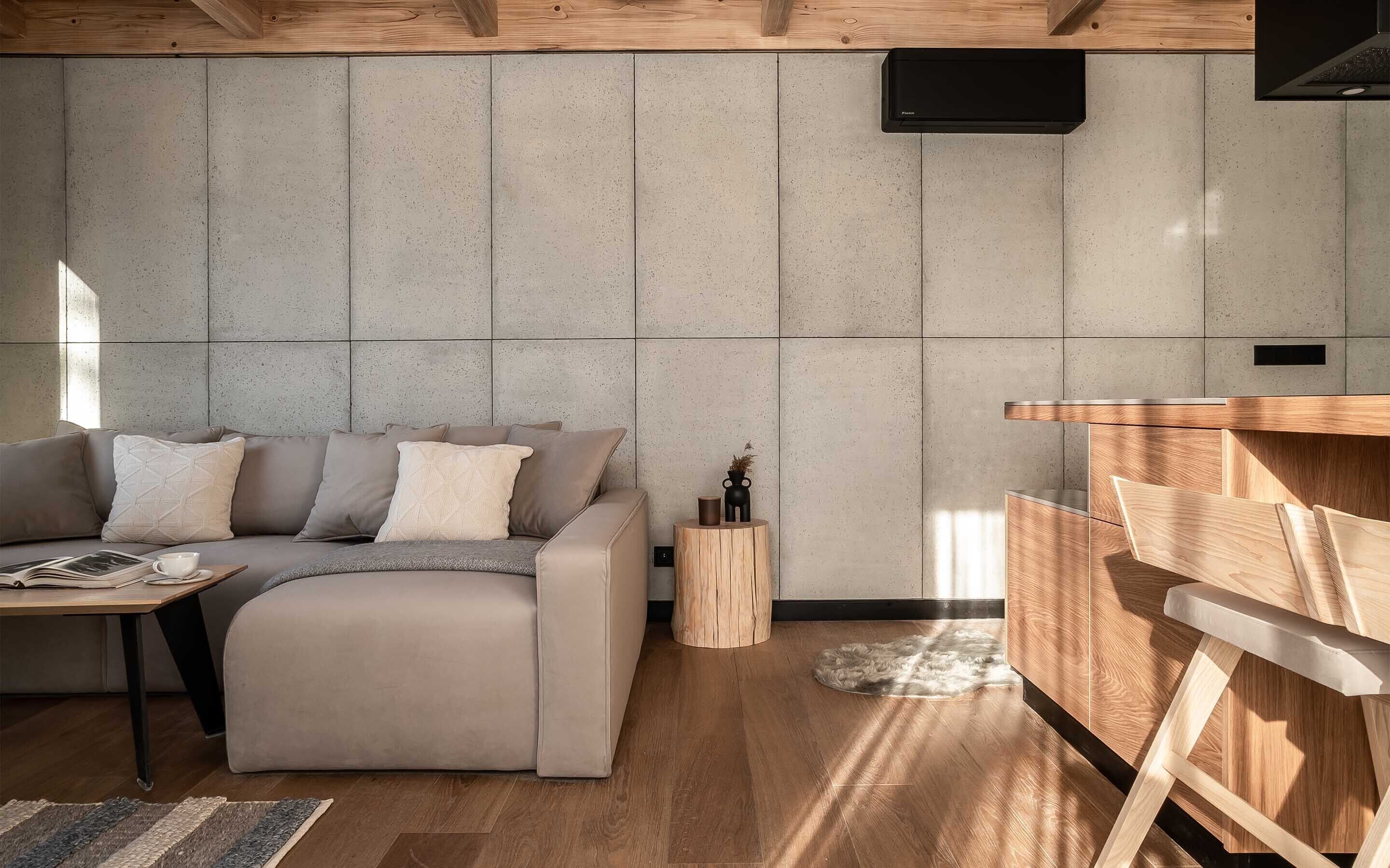 Een moderne woonkamer met een grijze bank, een houten salontafel en een klein bijzettafeltje met een plant.