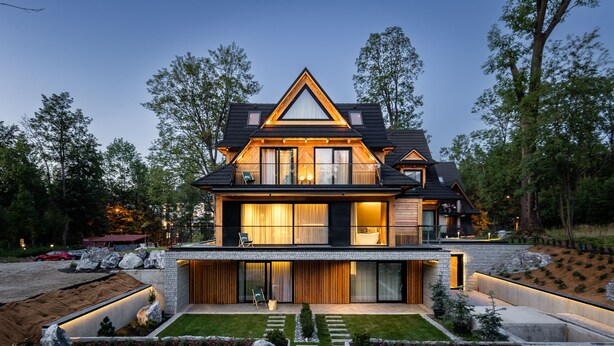 A modern two-story house with a stone facade, large windows, and a well-maintained lawn. - Villa T Apartments & SPA (Zakopane)