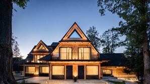 A modern house with a prominent triangular roof, large windows, and a well-lit entrance. - Villa T Apartments & SPA (Zakopane)