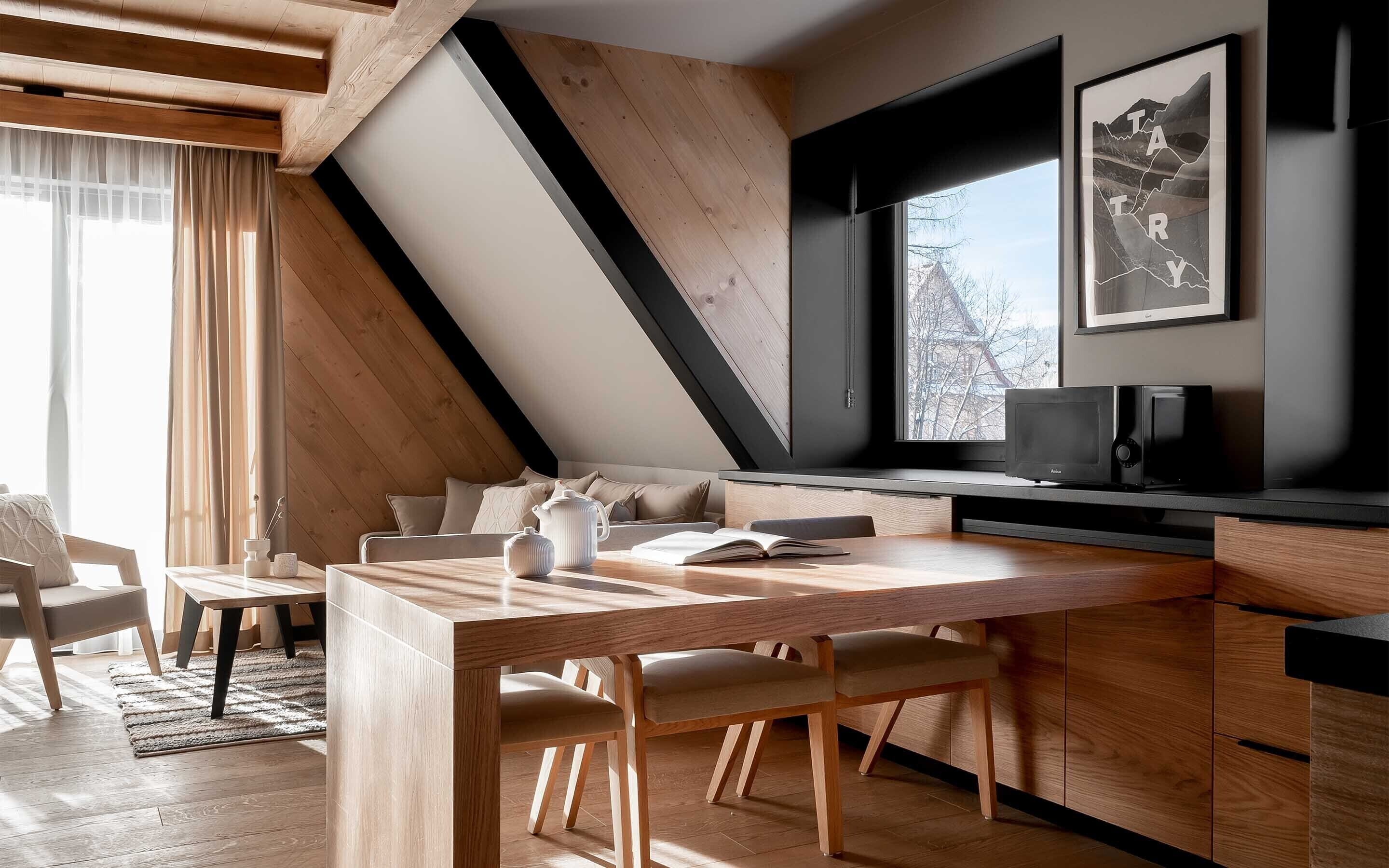 Une cuisine moderne avec une table à manger en bois, des chaises et un four à micro-ondes encastré.