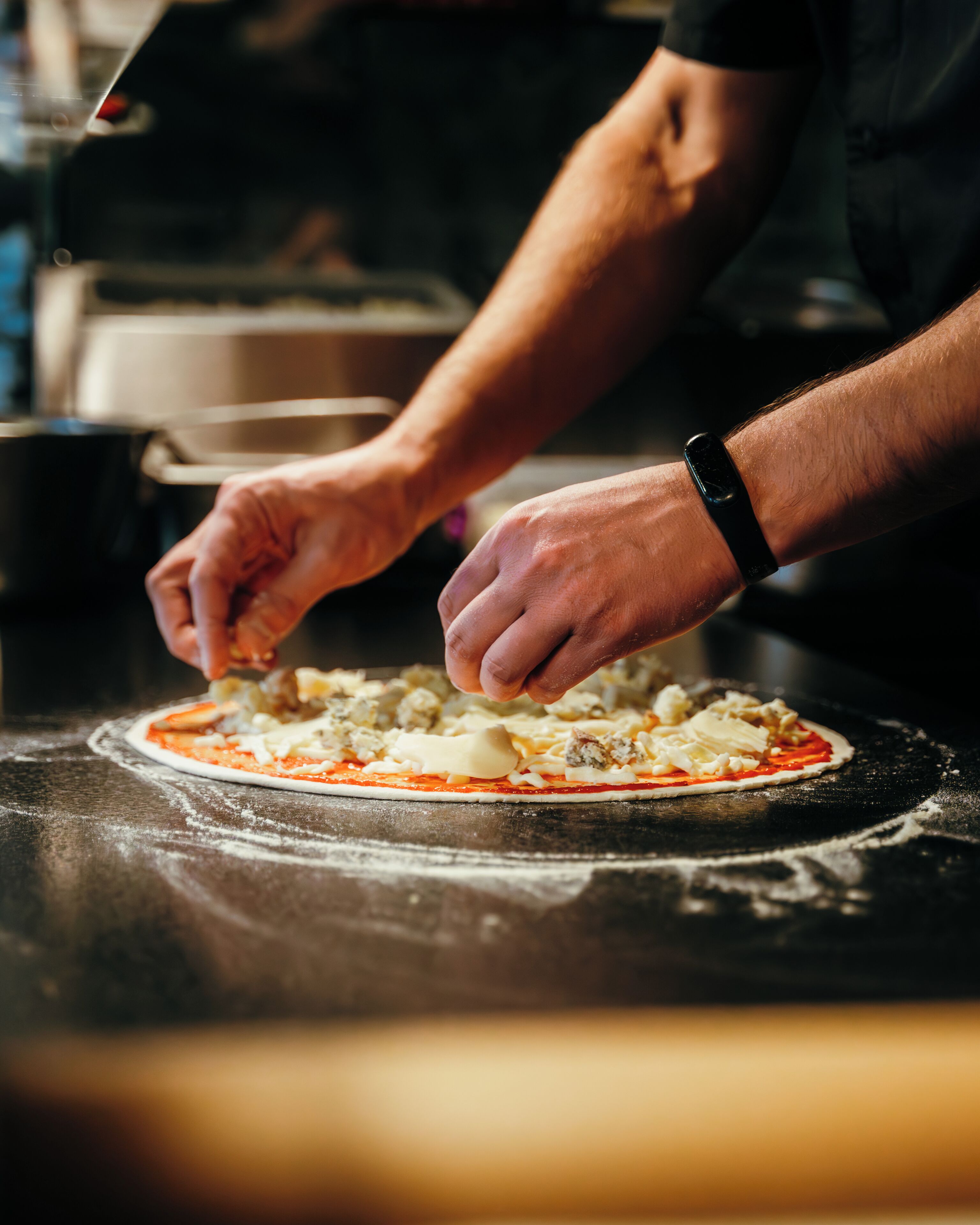 A person preparing a pizza on a table.