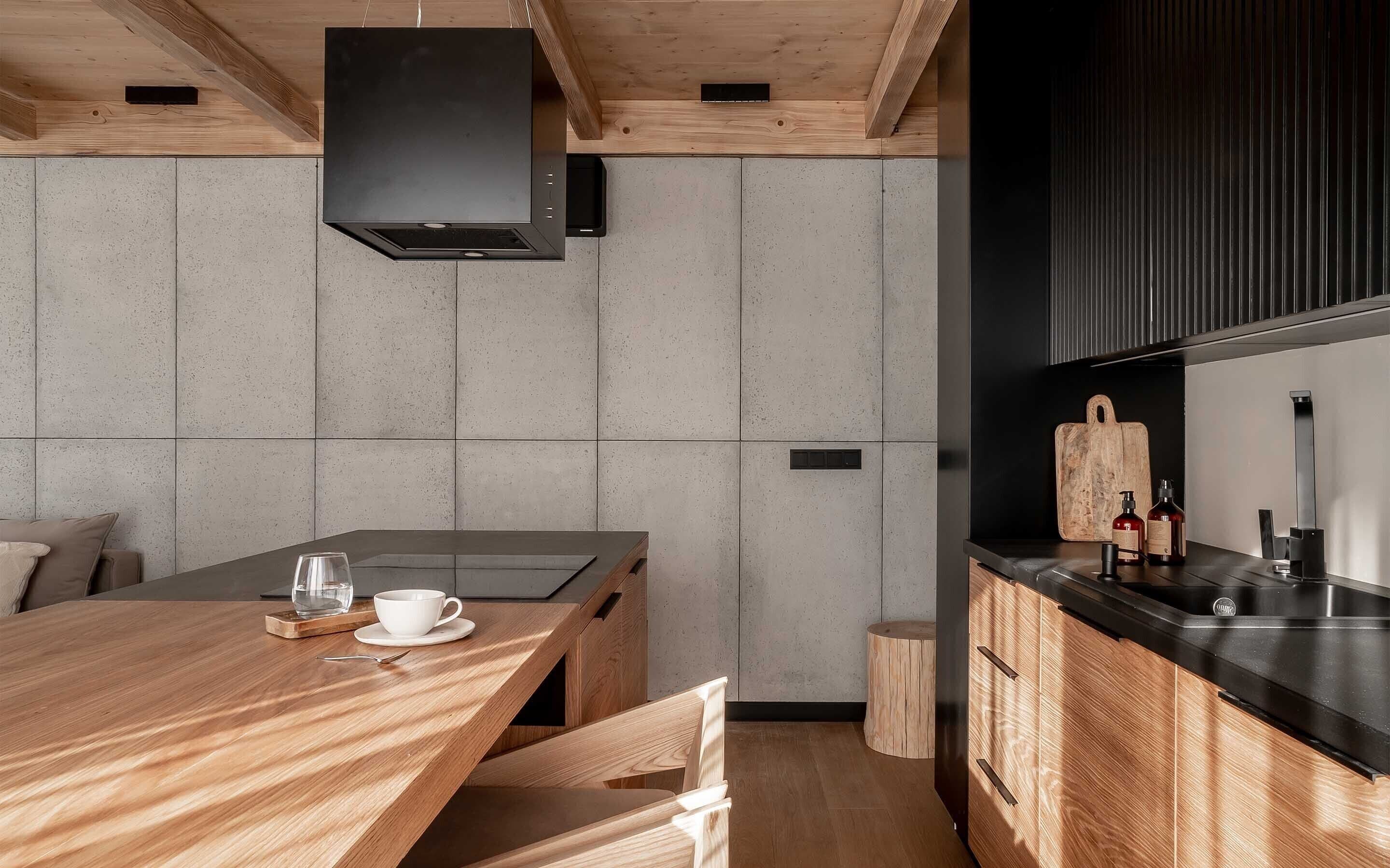 Una cocina moderna con una mesa de comedor de madera, una estufa empotrada y un salpicadero negro.