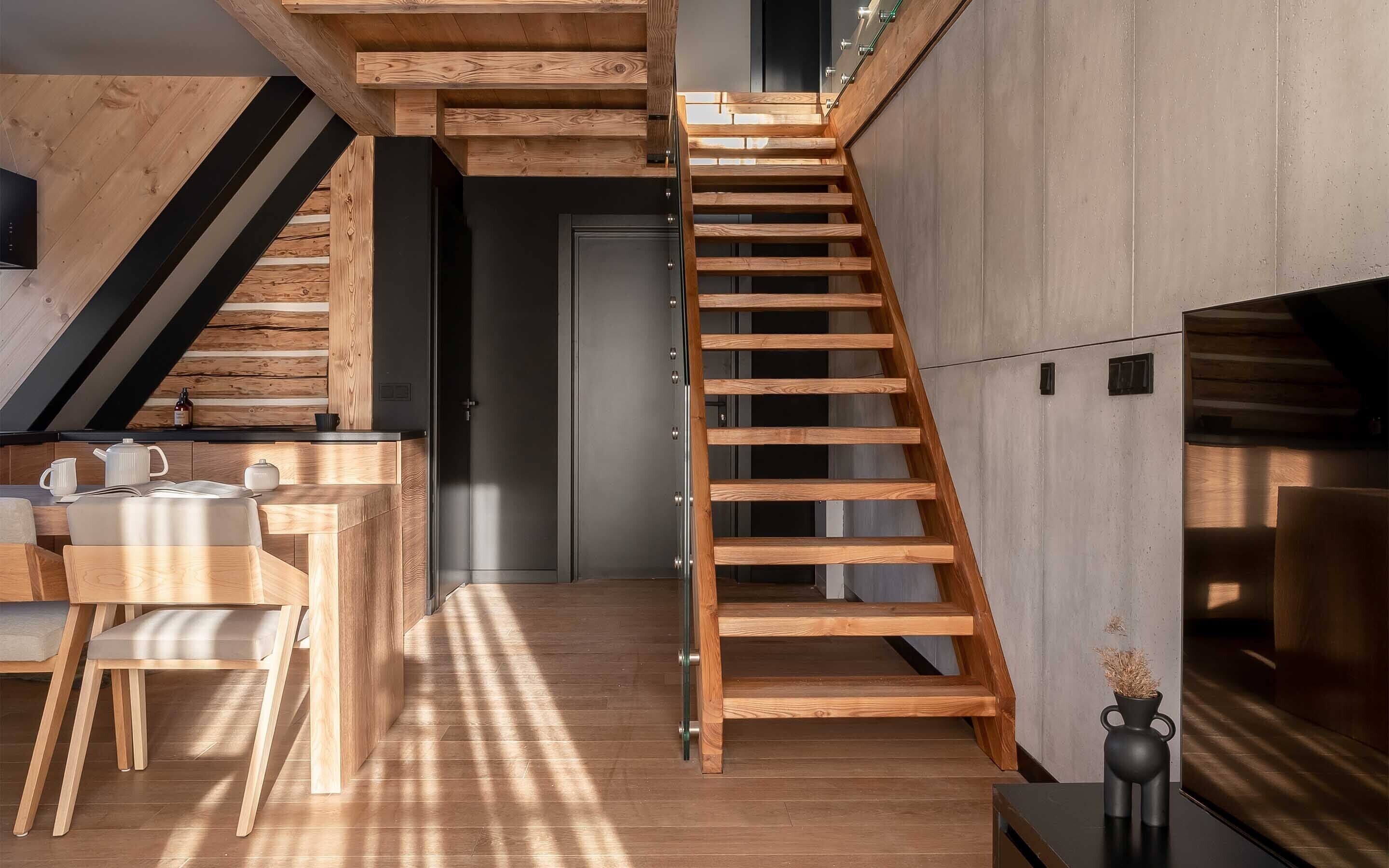 Eine moderne Küche mit Holzschränken, einem eingebauten Herd und einem Essbereich mit einem Holztisch und Stühlen.