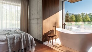 A modern bedroom with a large window, a bathtub, and a wooden chair. - Villa T Apartments & SPA (Zakopane)