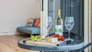 A round table with a bottle of wine, two glasses, grapes, cheese, and strawberries. - Chateau McNally - In the heart of Lancelin (Lancelin)