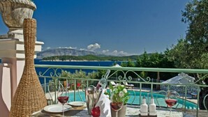 A table set for dining with a view of a pool and mountains in the background. - Villa Athena (Corfu)