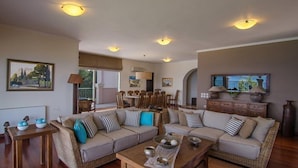 A spacious living room with a large sofa set, a dining area, and a television. - Villa Athena (Corfu)