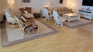 A living room with a sofa, two armchairs, a coffee table, and a TV. There are lamps and a painting on the wall. - Calypso unit 602, 6201 Coastal Hwy., Ocean City, Maryland 21842 (Ocean City)