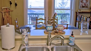 A kitchen with a wooden table, a sink, and a window with a view of chairs outside.