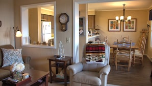 A living room with a sofa, armchair, coffee table, and a dining area with a table and chairs.