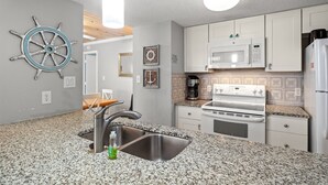 Una cocina moderna con encimeras de granito, electrodomésticos de acero inoxidable y decoración temática náutica.