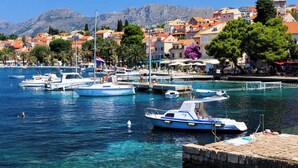 A marina with boats docked, a clear blue sea, and a town with historic buildings in the background. - Duka - One Bedroom Villa, Sleeps 2 (Dubravka, Konavle)