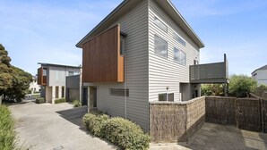A modern two-story house with a sloped roof, large windows, and a wooden extension on the side. - Anderson Central Townhouse - Walk to Shops & Beach (Torquay)