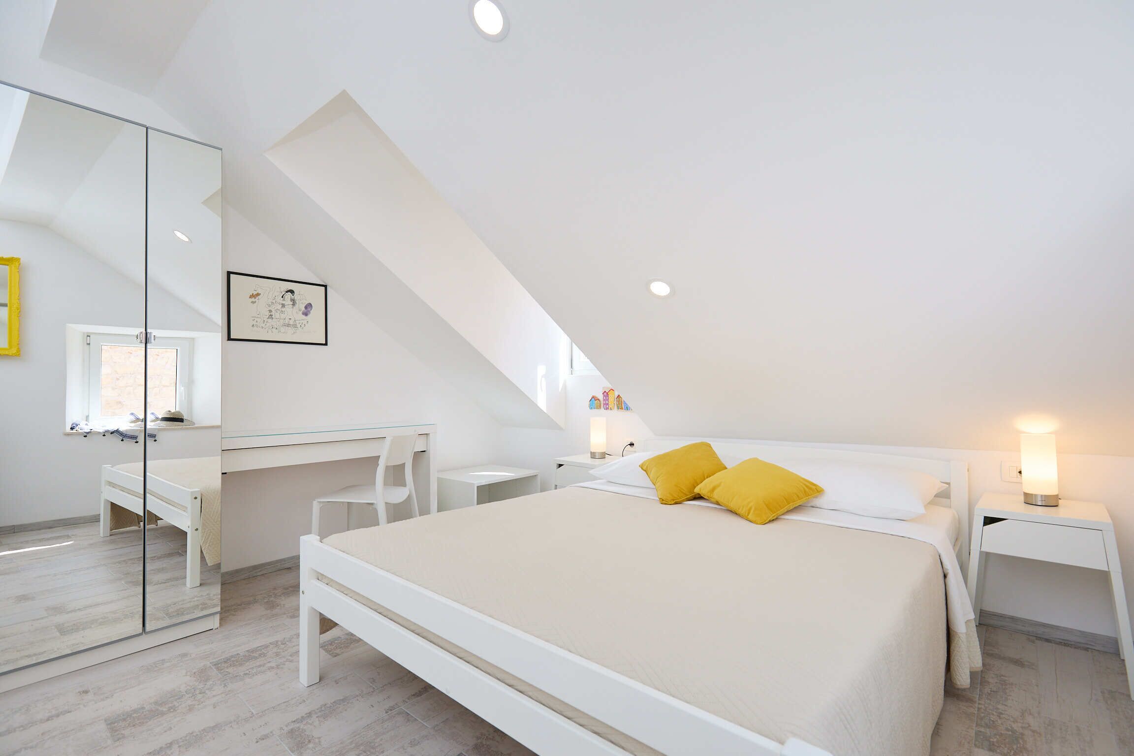 Ein modernes Schlafzimmer mit einem großen Bett, einem Schreibtisch und einem Spiegel.