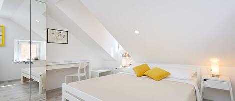 Ein modernes Schlafzimmer mit einem großen Bett, einem Schreibtisch und einem Spiegel.