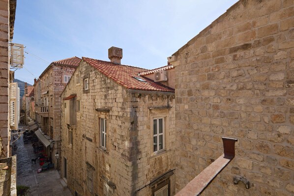 A narrow street with stone buildings, a red-tiled roof, and a visible air conditioning unit. - Apartment Nino 3 (Dubrovnik)