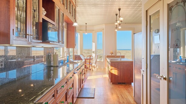 A modern kitchen with a large island, wooden cabinets, and a view to the outside. - PICKLEBALL! Two hot tubs, ocean views, 2 Homes, 8 Bedrooms, RecRooms (K&KGst) (Long Beach)