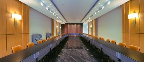 A conference room with a long table, chairs, and a marble floor.