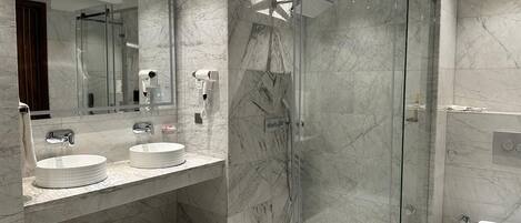 Een moderne badkamer met twee wastafels, een douche met glazen wand en een grote spiegel.