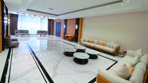 Un hall d’entrée spacieux avec un sol en marbre, un ensemble de canapés et une table basse.