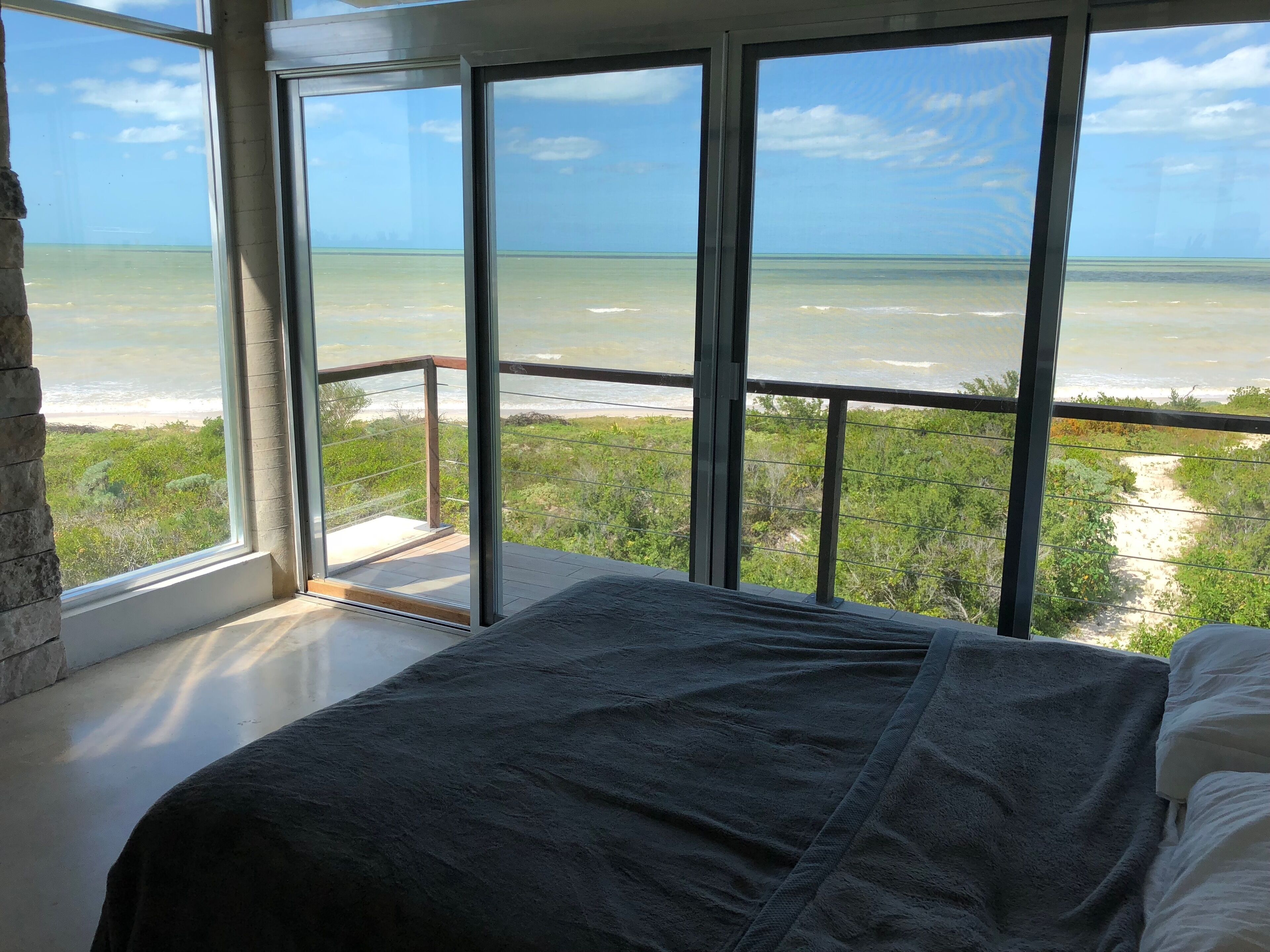 Une chambre avec une grande fenêtre donnant sur une plage et l’océan.