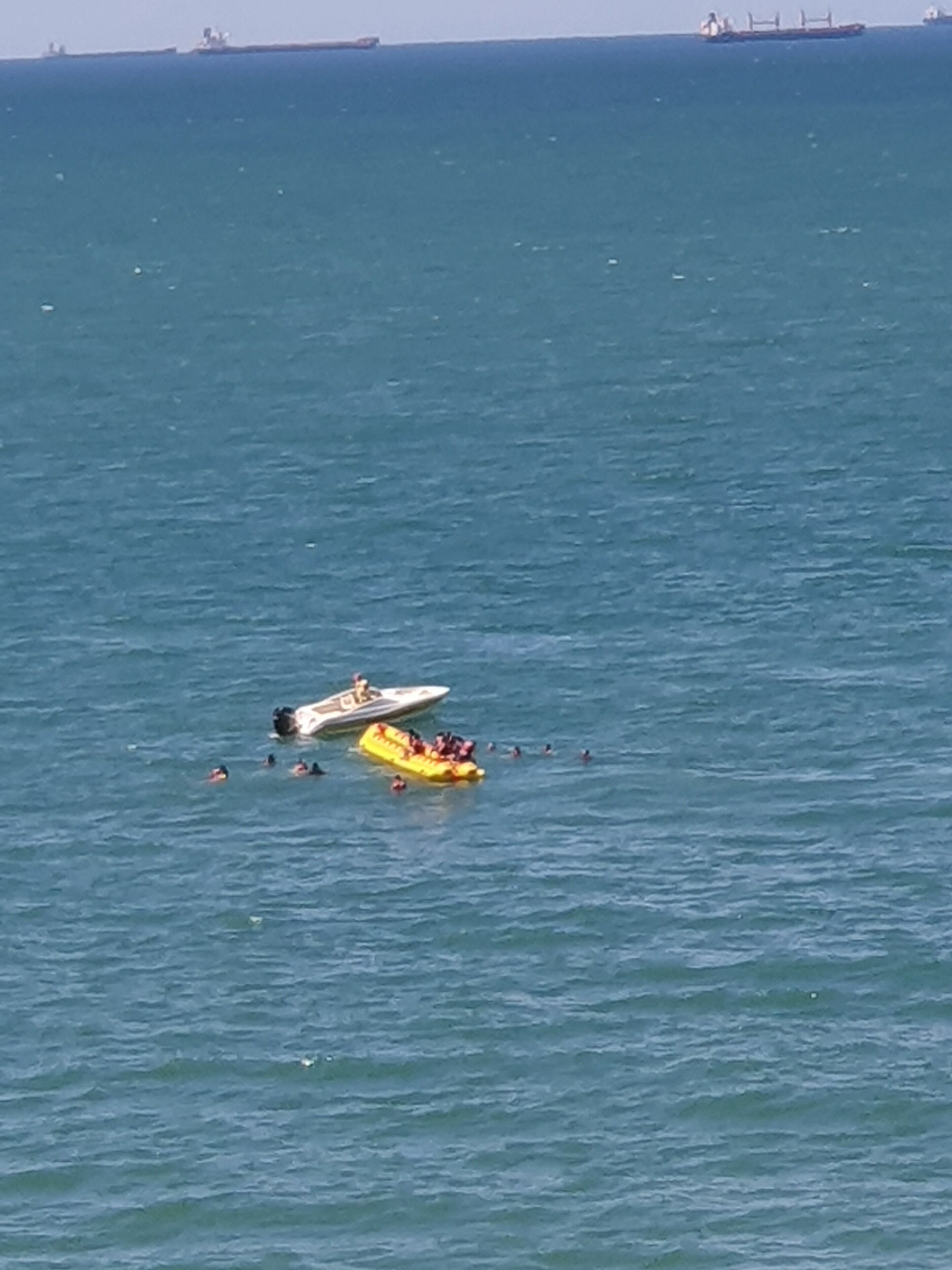 Un bote en el agua con gente nadando a su alrededor.