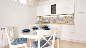 A modern kitchen with white cabinets, a tiled backsplash, and a dining table set with blue plates and glasses.