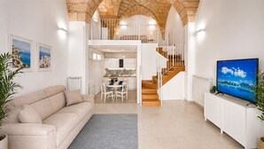 A spacious living area with a sofa, dining table, and staircase leading to an upper level.