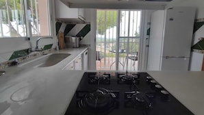 A kitchen with a gas stove, a sink, and a window overlooking a patio.