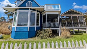 Et toetagers hus med blå facade, balkon og veranda.