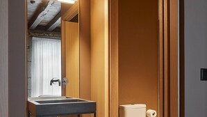 Un baño moderno con tocador de madera, un espejo, un inodoro y un perchero para toallas.
