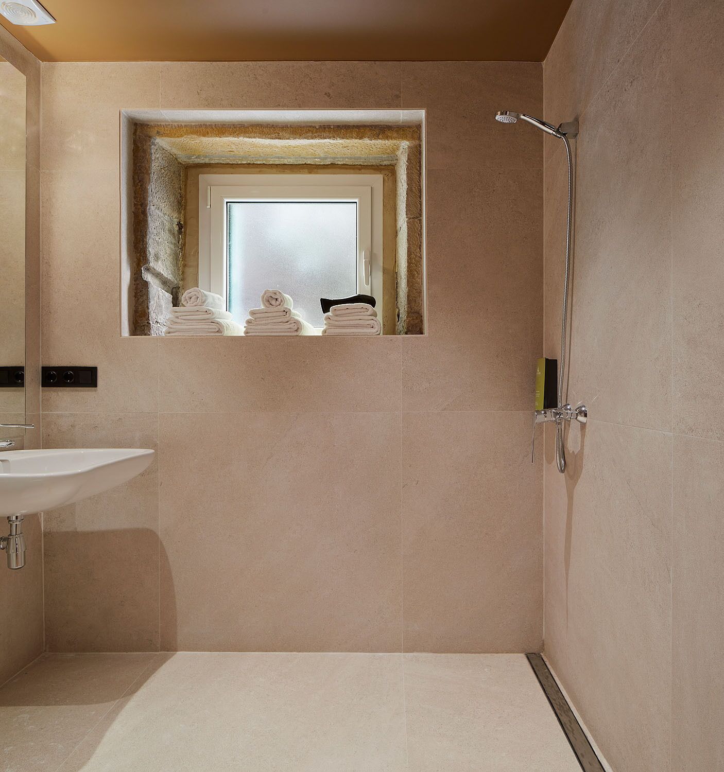 Ein Badezimmer mit Dusche, Waschbecken und einem Fenster, ausgestattet mit Handtüchern.
