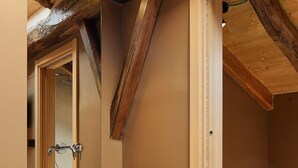 Un baño moderno con techo de madera, un lavamanos negro y toallas blancas.