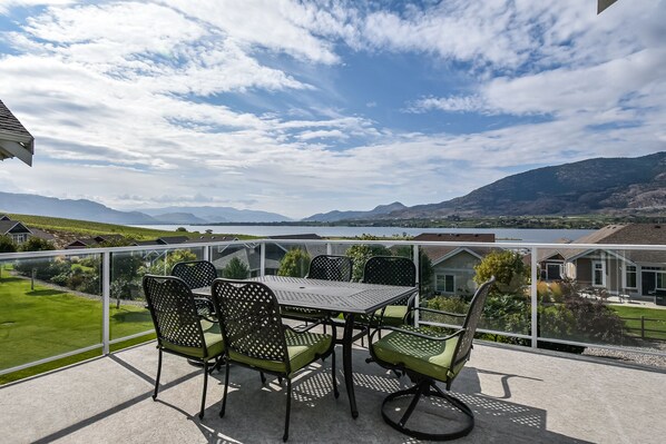 Ein Balkon mit Tisch und Stühlen mit Blick auf einen See und Berge.