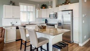 A modern kitchen with white cabinets, stainless steel appliances, and a central island with seating. - Beach, boatslip, 2 pools, 2 hottubs, 4 bdrm house sleeps 12 (Oliver)
