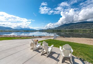A lakeside patio with Adirondack chairs and a concrete deck.