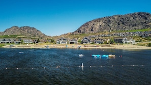 A waterfront property with multiple houses, a beach, and mountains in the background.