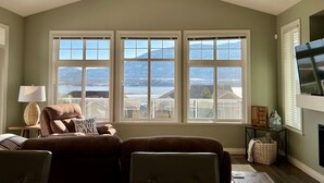 A living room with a large window, a sofa, a TV, and a fireplace. - Beach, boatslip, 2 pools, 2 hottubs, 4 bdrm house sleeps 12 (Oliver)