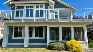 A two-story house with a balcony, large windows, and a well-maintained lawn. - Beach, boatslip, 2 pools, 2 hottubs, 4 bdrm house sleeps 12 (Oliver)