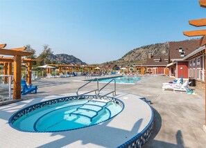 Ein Poolbereich mit mehreren Pools, Liegestühlen und Holz-Pergolen.