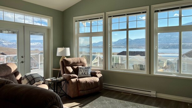 A living room with a view of mountains and a lake through large windows. - Beach, boatslip, 2 pools, 2 hottubs, 4 bdrm house sleeps 12 (Oliver)